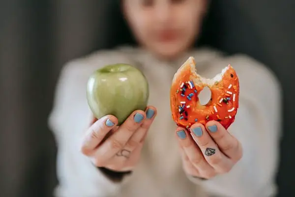 Woman holding donut and apple