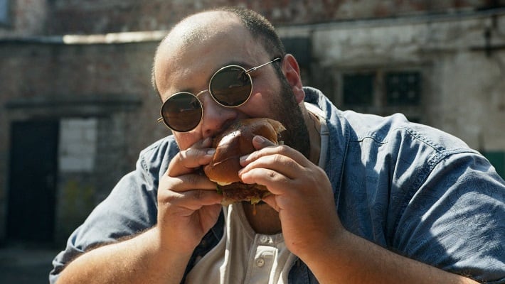 Fat man eating a hamburger