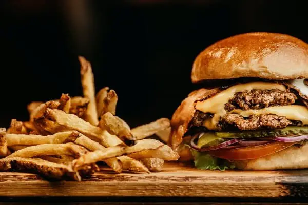 A fatty hamburger and fries on a cutting board