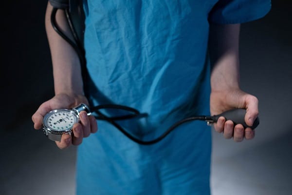 A doctor holding a stethoscope against a dark background