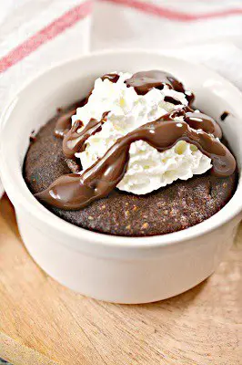 Keto air fryer mini brownie cake with whipped cream and chocolate sauce in a bowl
