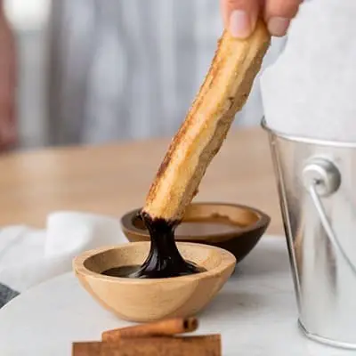Air fryer churro being dipped into sauce
