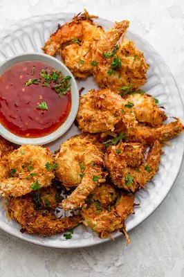air fryer keto coconut shrimp on a plate with sauce