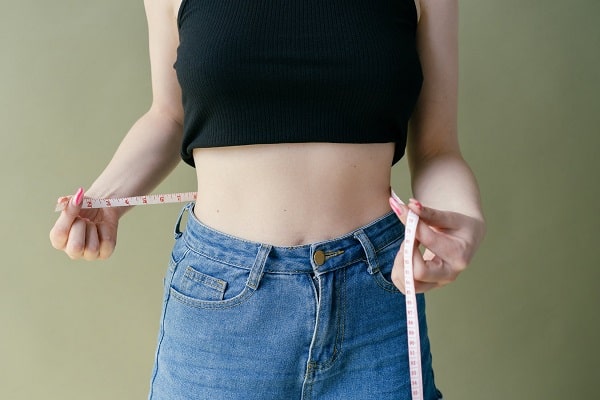 woman measuring stomach with cloth tape measure