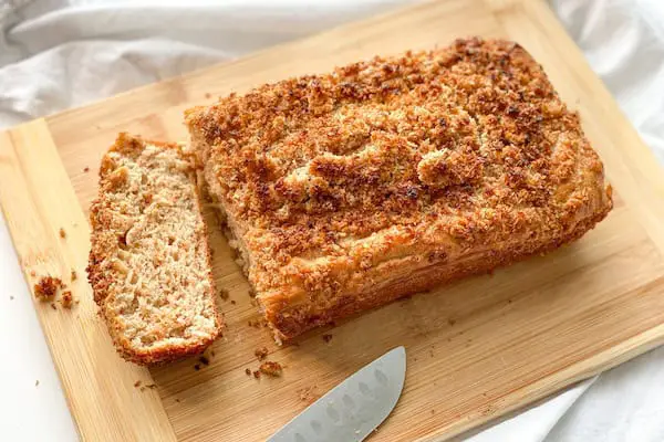 Keto coffee cake on a chopping board with one piece sliced off