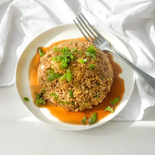 keto fried rice with pork on a white plate with silver fork